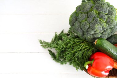 Hasır kase beyaz ahşap arka planda farklı taze sebzelerle