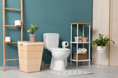 Tuvalet, çöp tenekesi, merdiven ve raf ünitesi mavi duvarın yanında.