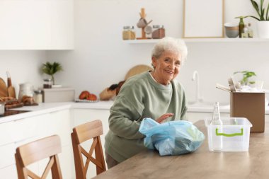 Mutfaktaki çöpleri sıralayan kıdemli kadın.