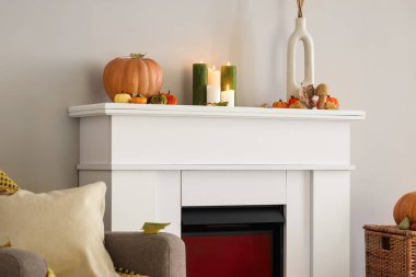 Şöminenin üzerinde yanan mumlarla yanan balkabakları odada, ışık duvarının yanında.