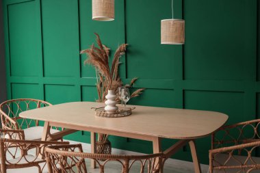 Yemek masasında yeşil duvarın yanında sandalyeler var.