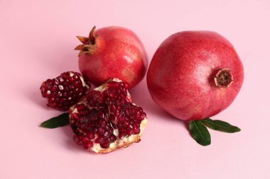 Pembe arka planda taze nar ve yapraklar.