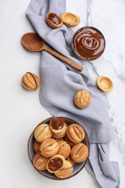 Beyaz arka planda kaynamış yoğunlaştırılmış sütle ceviz şeklinde kurabiyeler.