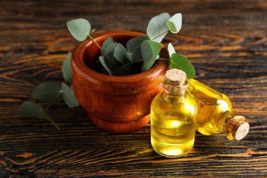 Okaliptüs dalları ve ahşap zemin üzerinde gerekli yağ şişeleriyle havan topu.