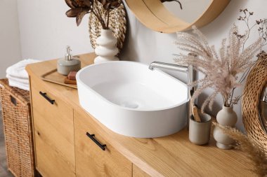 Lavabolu ahşap dolap, kurumuş çiçekler ve şık banyoda banyo aksesuarları.