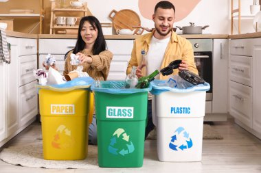 Evdeki çöp bidonlarını düzenleyen genç bir çift. Küresel Geri Dönüşüm Günü