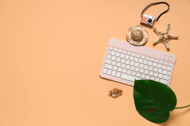 Kamera ve turuncu arka planda plaj dekoru olan bilgisayar klavyesi
