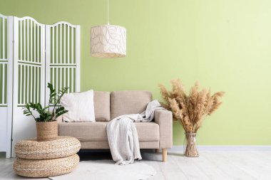 Gri kanepeli, puflu ve katlanır perdeli oturma odasının içinde.