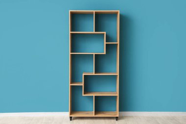 Mavi duvarın yanındaki boş ahşap raf ünitesi.