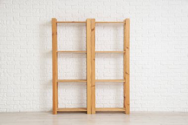 Beyaz tuğla duvarın yanında boş ahşap raf ünitesi