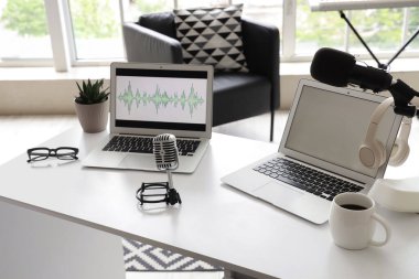 Podcaster 'ın iş yeri. Stüdyoda dizüstü bilgisayarlar ve mikrofon var.