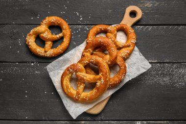 Siyah ahşap arka planda lezzetli çubuk kraker kesme tahtası, yakın plan.