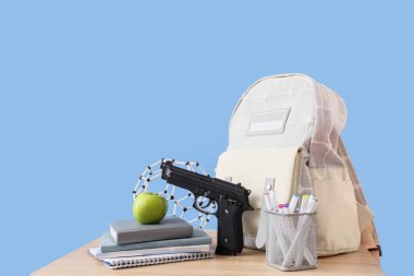 Sırt çantasında silah, elma, kitap ve moleküler model mavi arka planda. Okul çekim konsepti