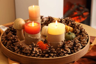 Odada yanan mumlar ve sonbahar dekoru olan tepsi, yakın plan.