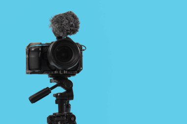 Mavi arka planda üç ayaklı ön camlı modern fotoğraf makinesi