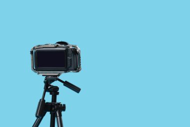Mavi arka planda üç ayaklı modern fotoğraf makinesi