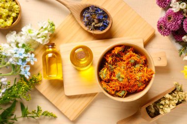 Ahşap zemin üzerinde kurumuş çiçekler olan gerekli yağ şişeleri.