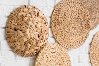 Beyaz tuğla duvarda asılı farklı hasır paspaslar