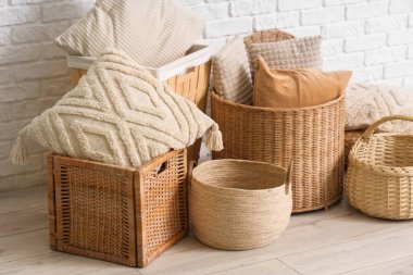 Beyaz tuğla duvarın yanında farklı hasır sepetler.