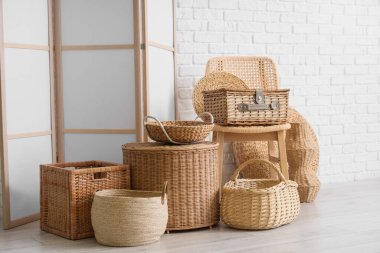 Şık oturma odasının içinde rattan sandalye, katlanır perde ve farklı hasır sepetler var.