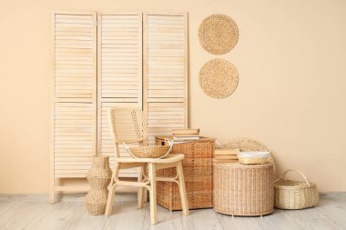 Şık oturma odasının içinde rattan sandalye, katlanır perde ve farklı hasır sepetler var.