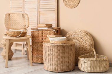 Şık oturma odasının içinde rattan sandalye, katlanır perde ve farklı hasır sepetler var.