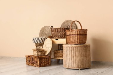 Farklı hasır sepetler ve şık bir odada bej duvarın yanındaki masa.