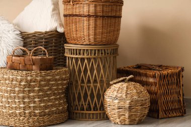 Bej duvarın yanında farklı hasır sepetler şık bir odada, yakın plan.