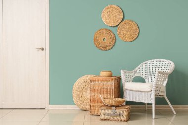 Şık oturma odasının içinde rattan koltuk ve farklı hasır sepetler var.