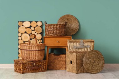 Farklı hasır sepetler ve şık bir odada mavi duvarın yanındaki masa.