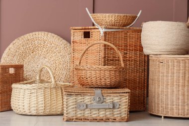 Kahverengi duvarın yanında farklı hasır sepetler.