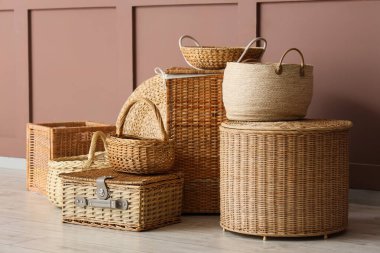 Kahverengi duvarın yanında farklı hasır sepetler.