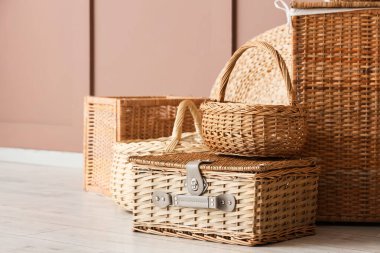 Kahverengi duvarın yanında farklı hasır sepetler.