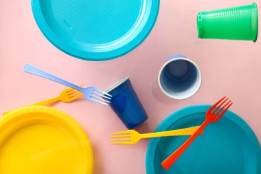 Pembe arka planda renkli plastik sofra takımı havada asılı duruyor