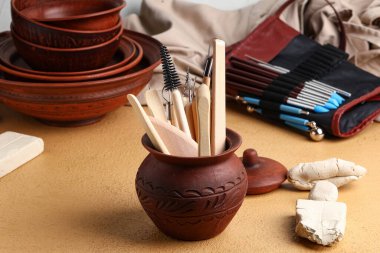 Masanın üzerinde heykel aletleri olan seramik kap