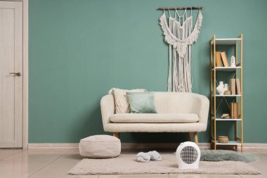 Beyaz koltuğun yanında modern elektrikli vantilatör ısıtıcısı var.