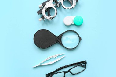 Gözlüklü optik deneme çerçevesi, kontak lensler ve mavi arka planda büyüteç için ayarlandı