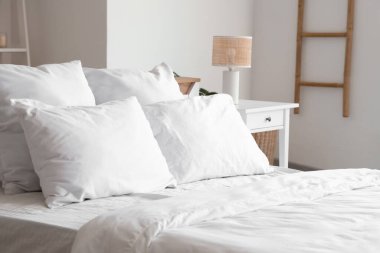 Yatak odasında yumuşak yastıkları ve beyaz battaniyesi olan rahat bir yatak.