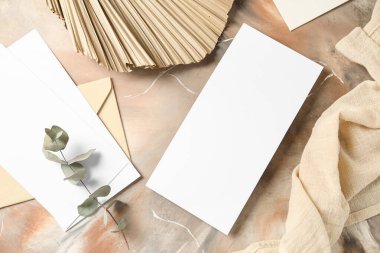 Boş kartlı zarf, okaliptüs dalı, kurumuş palmiye yaprağı ve grunge arka planda kumaş.