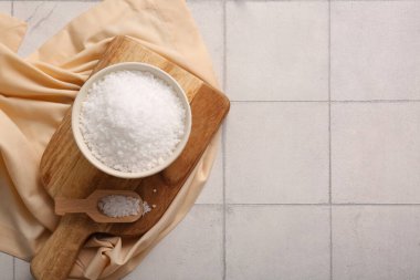 Hafif fayans zemininde bir kase deniz tuzu ve peçeteyle ahşap tahta.