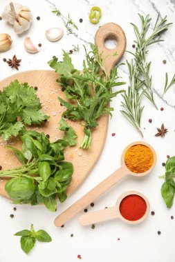Ahşap kesim tahtası, mermer arka planda bitkiler ve baharatlar, yakın plan.