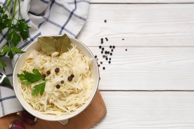 Lezzetli lahana turşulu kase ve beyaz ahşap arka planda farklı baharatlar.