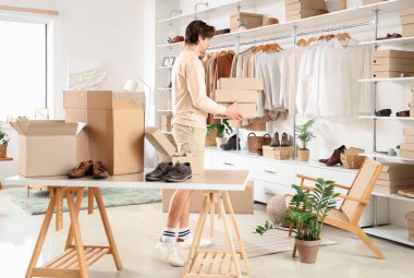 Soyunma odasında kostüm kutuları ve şık giysileri olan yakışıklı bir genç.