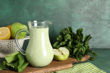 Bir sürahi taze ıspanaklı meyve püresi, yeşil arka planda elma.