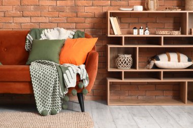 Interior of living room with stylish cushions on red sofa and shelf unit