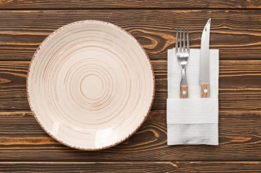 Çatal bıçak takımı ve tahta arka planda kağıt peçete.