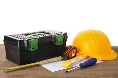 Sert şapka, alet çantası, ev planı ve beyaz arka plana karşı ahşap masadaki inşaat araçları