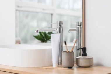 Banyoda lavabonun yanında duran bambu diş fırçası ve yapıştırıcılı tutucu.