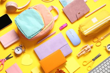 Sarı arka planda modern cep telefonu ve okul malzemelerine sahip kompozisyon