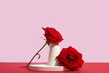 Gri arka planda kırmızı masada güzel kırmızı gül çiçekleri olan dekoratif podyumlar